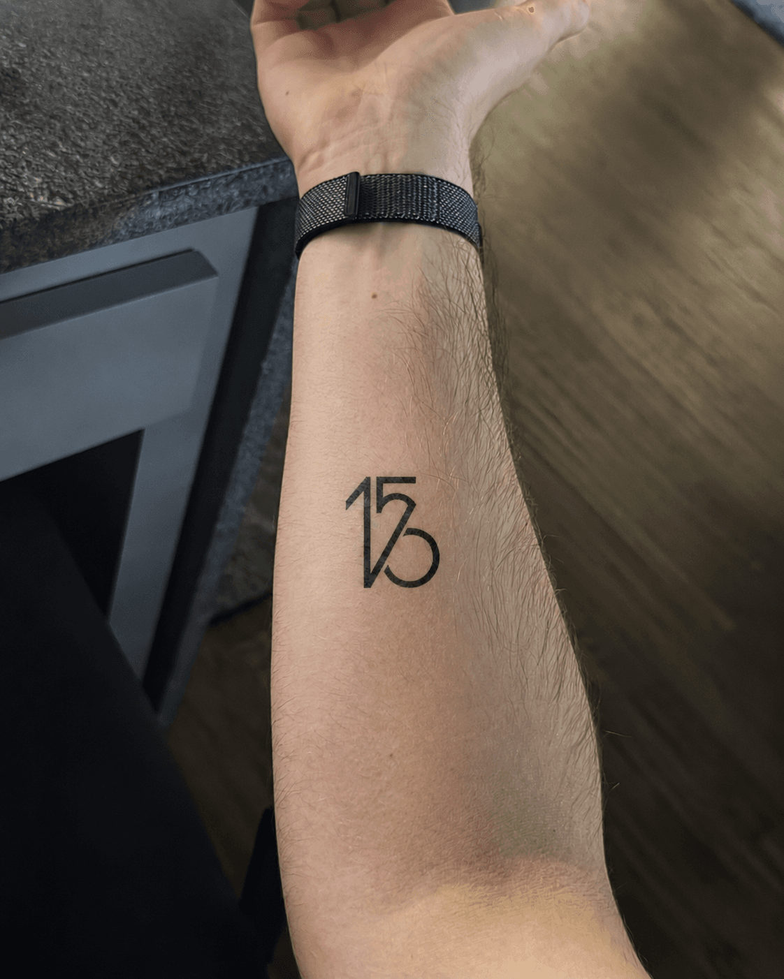 The 156 / watch monogram inked on a forearm near the wrist.